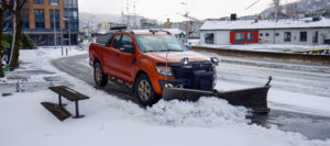 Truck with plow clearing street by business